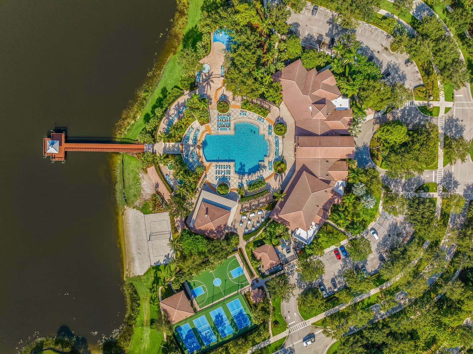 Resort style club house, with beautiful pool, tennis and pickleball courts, and a dock extending into a lake.