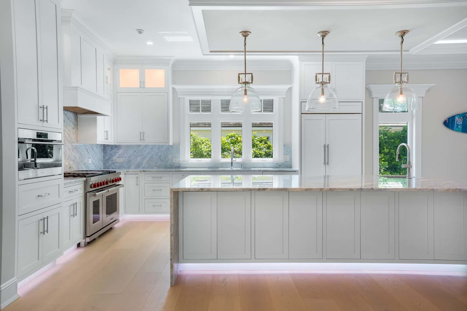 One point view of a beautiful kitchen with under cabinet lighting, granite tops, and nice pendant lights.